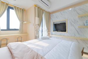 um quarto com uma grande cama branca e uma televisão em RedLiving Apartemen Jakarta Living Star - BoboRooms em Jakarta