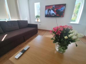 uma sala de estar com um sofá e um vaso de flores sobre uma mesa em Beautiful house in the heart of a golf course. em Manchester