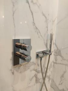 La salle de bains est pourvue d'une douche et d'un mur en marbre blanc. dans l'établissement Beautiful family flat nearby the Flea Market, Stade de France, Montmartre, à Saint-Ouen