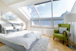 a bedroom with a bed and a green chair at Venus Apartments - Skylit - Deluxe Loft with Skylight in Budapest