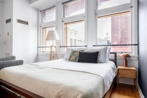 een slaapkamer met een bed met witte lakens en ramen bij Loop Studio w Gym Doorman nr L Parks CHI-300 in Chicago +13 foto's