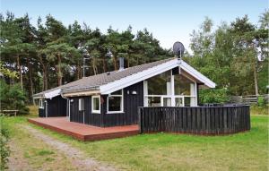 a small black house with a wooden deck at Holiday Home Røllikevej Knebel Ii in Knebel