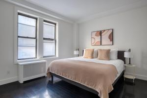 a white bedroom with a bed and two windows at Midtown 2br w doorman wd nr Central Park NYC-1246 in New York