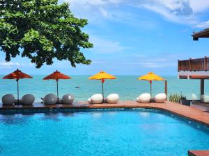 a swimming pool with umbrellas and the ocean at Yotaka Khanom in Ban Phang Phrao