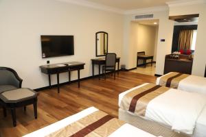 a hotel room with two beds and a desk at Grand Darul Makmur Hotel Kuantan in Kuantan