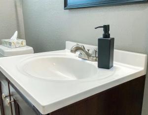 - un lavabo blanc dans la salle de bains avec un distributeur de savon dans l'établissement Oak Forest Cottage, à Little Rock