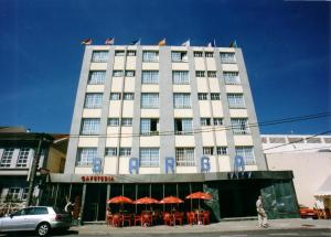 ein Gebäude mit Tischen und Sonnenschirmen davor in der Unterkunft Hotel Sarga in Cabañas