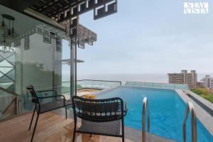 un balcón con 2 sillas y una piscina en StayVista Sea Pearl View Beach View with Rooftop Pool, en Dapoli