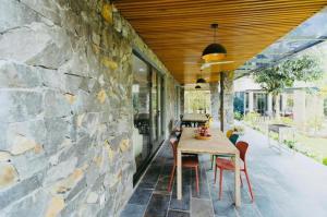 comedor al aire libre con pared de piedra en An Villa Venuestay, en Tam Ðảo