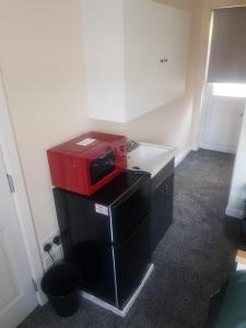 um micro-ondas vermelho sentado em cima de um balcão num quarto em Self contained room, en-suite with separate lockable front door, located in an exclusive area em Wednesbury