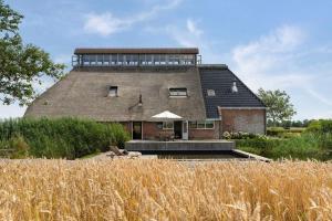 a large house with a thatched roof in a field at Wadhuis met spectaculair uitzicht op zee! in Nes