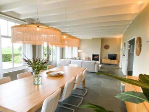 a dining room with a wooden table and white chairs at Wadhuis met spectaculair uitzicht op zee! in Nes