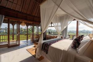 a bedroom with a bed in a room with windows at Barong Bali Resort Ubud in Ubud