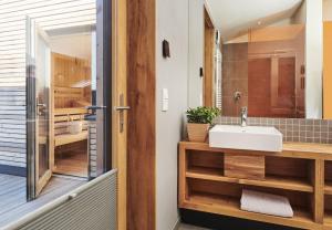 La salle de bains est pourvue d'un lavabo blanc et d'une baignoire. dans l'établissement Gud Jard Lodge Nr 01 - Design-Ferienhaus mit exklusiver Ausstattung, à Pellworm