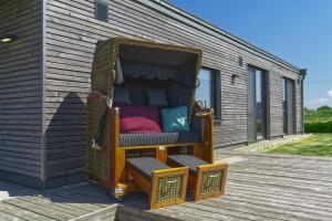 une chaise assise au-dessus d'une terrasse en bois dans l'établissement Gud Jard Lodge Nr 01 - Design-Ferienhaus mit exklusiver Ausstattung, à Pellworm
