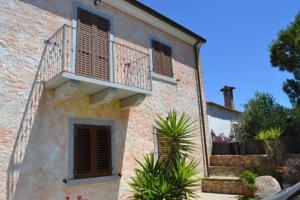 a building with a balcony and a staircase on it at Agriturismo Lu Stabbiacciu in Aglientu
