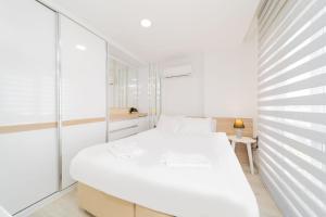 - une chambre blanche avec un lit et un miroir dans l'établissement Residence w Shared Pool 3 min to Mall of Antalya, à Antalya