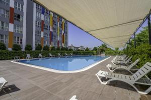 una piscina con tumbonas y un edificio en Residence w Shared Pool 3 min to Mall of Antalya en Antalya