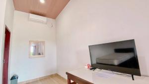uma sala de estar com televisão numa parede branca em Amadeo Guest House em Ratodena