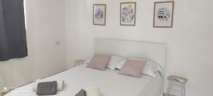 a white bedroom with a white bed with pink pillows at Neve Tsedek Rooftop in Tel Aviv