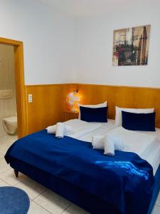 Schlafzimmer mit einem großen Bett mit blauer und weißer Bettwäsche in der Unterkunft Hotel La Ferté in Stuttgart