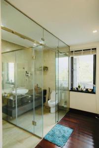 a bathroom with a glass shower and a toilet at An Villa Venuestay in Tam Ðảo