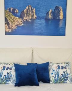ein Gemälde, das über einer Couch hängt, mit Kissen drauf in der Unterkunft Romy Blu in Capri
