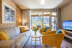 a living room with a couch and a tv at SWISSPEAK Resorts Meiringen in Meiringen