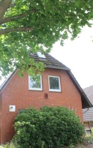 a red brick house with two windows at Ferienhaus Strandnah - Wohnung 1 in Otterndorf