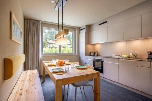 a kitchen with a wooden table and a dining room at SWISSPEAK Resorts Meiringen in Meiringen