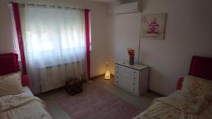 a bedroom with two beds and a dresser and a window at Center Una Apartment in Bihać