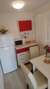 Il comprend une cuisine équipée d'un réfrigérateur blanc et d'une table avec des chaises. dans l'établissement Center Una Apartment, à Bihać