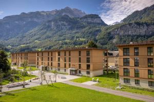 SWISSPEAK Resorts Meiringen في ميرينغين: عمارة سكنية فيها جبال في الخلفية