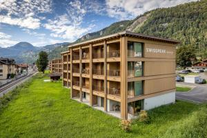 an apartment building with a green lawn in front of a mountain at SWISSPEAK Resorts Meiringen in Meiringen