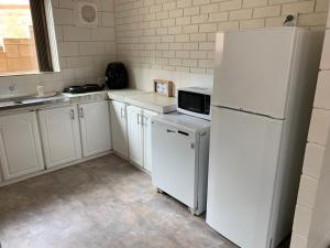 cocina con electrodomésticos blancos y nevera blanca en Harbour View 49 Urch Street Unit 7, en Geraldton