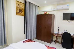 a room with a bed and a cabinet and a desk at Olympic Hotel in Kigali