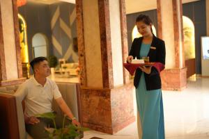 un hombre y una mujer de pie junto a una mujer en Pleiku Hotel by Gia Lai Tourist en Pleiku