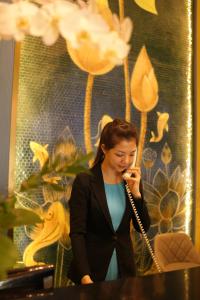 a woman in a suit talking on a cell phone at Pleiku Hotel by Gia Lai Tourist in Pleiku
