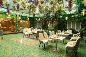 um restaurante com mesas, cadeiras e plantas em Pleiku Hotel by Gia Lai Tourist em Plây Ku