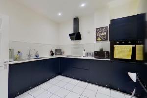 a large kitchen with blue cabinets and white tile floors at 2 Sea View Margate in Margate