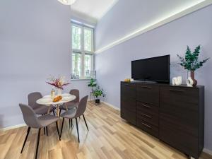 een woonkamer met een tafel en stoelen en een televisie bij Apartament przy Rynku Długa 23 in Krakau