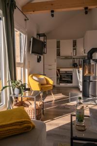 ein Wohnzimmer mit einem gelben Stuhl und eine Küche in der Unterkunft Ferienwohnung Panorama Teichblick in Heldritt