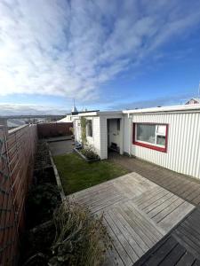 a white house with a deck and a yard at Guesthouse 10 min from Airport. in Njarðvík