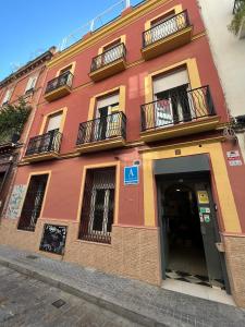 a red building with balconies on a street at Hostel A2C in Seville