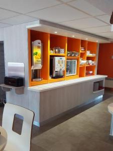 un mostrador restaurante con armarios naranjas y caja registradora en Premiere Classe Creil - Villers Saint Paul, en Villers-Saint-Paul