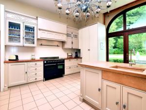 a large kitchen with white cabinets and a chandelier at Luxurious castle with hot tub in the Belgian in Jamoigne
