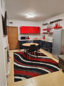 een keuken met een tafel en een keuken met rode kasten bij Апартамент "Red&Black" в Гранд Манастира - Пампорово in Pamporovo