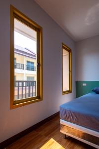 een slaapkamer met een bed en een raam met een balkon bij โรงแรมเชียงคำรักคุณ in Chiang Kham