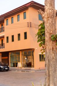 ein Gebäude mit einem Baum davor in der Unterkunft โรงแรมเชียงคำรักคุณ in Chiang Kham