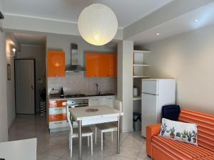 cocina con mesa y cocina con armarios de color naranja en casa vacanze La Farfalla en Capo dʼOrlando